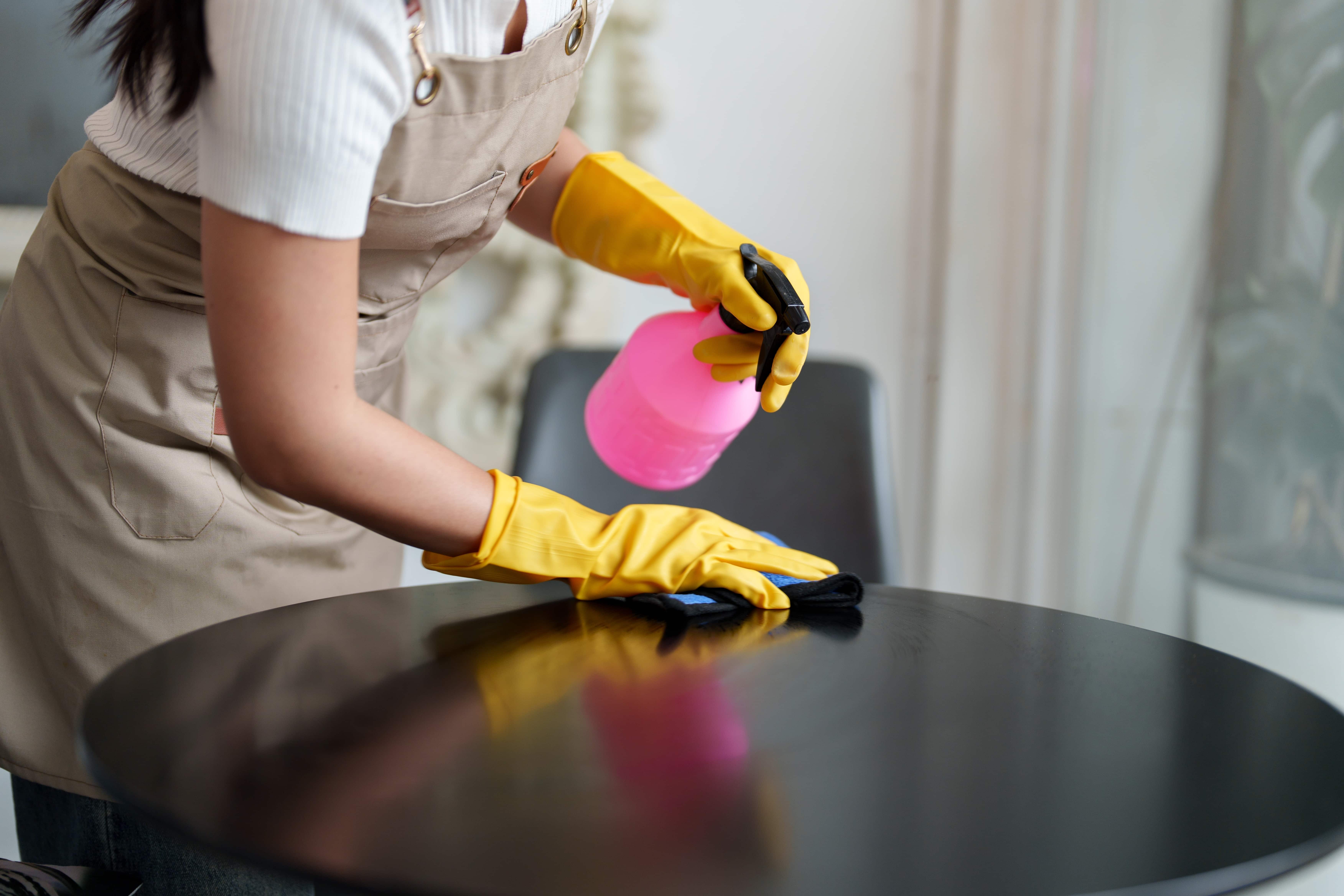 A cleaner polishing a dining table